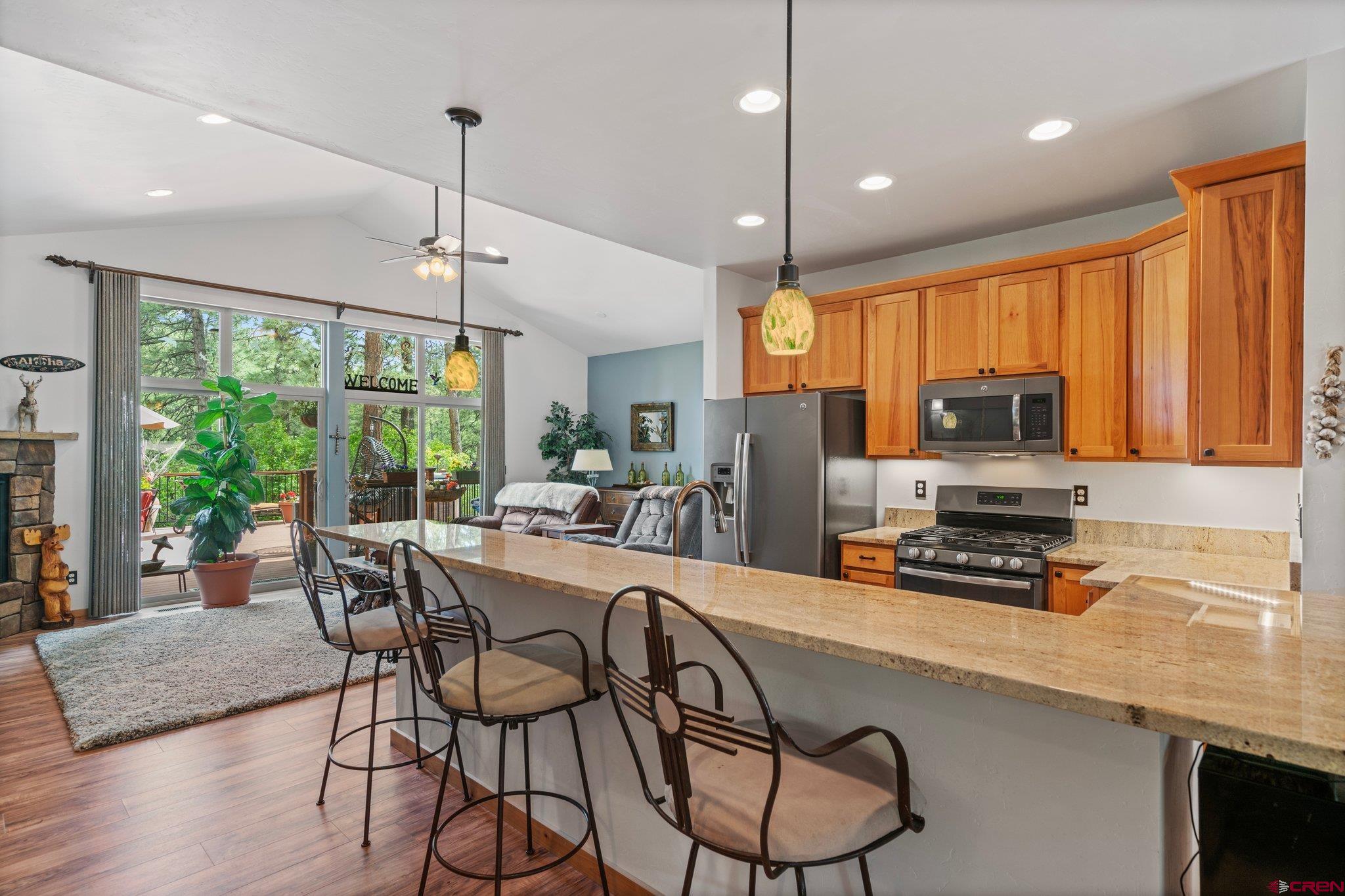 105 Window Lake Trail Durango, CO 81301 - Photo 15 of 36 a kitchen with stainless steel appliances granite countertop a stove top oven a refrigerator a sink a dining table and chairs with wooden floor