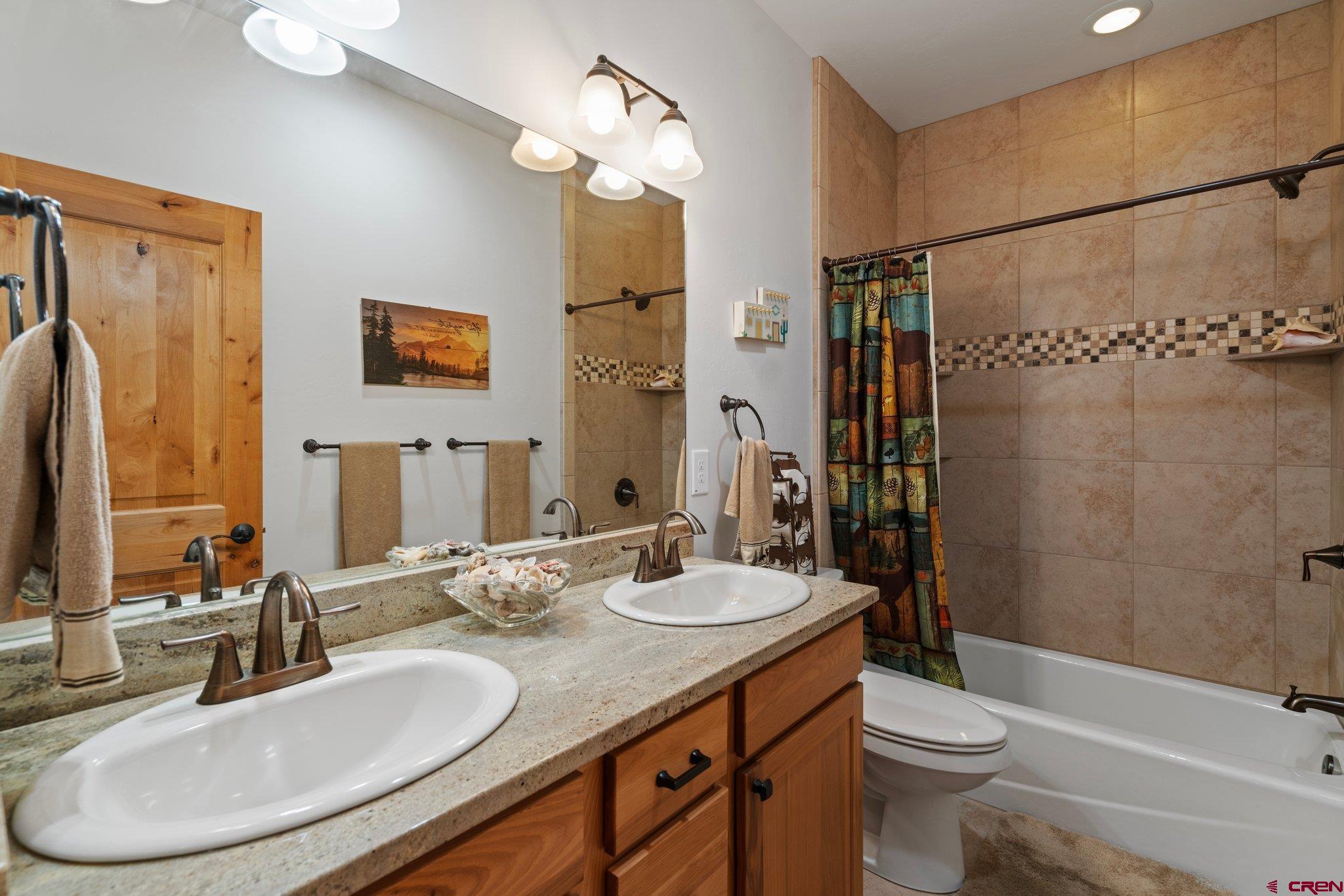 105 Window Lake Trail Durango, CO 81301 - Photo 23 of 36 a bathroom with a granite countertop sink toilet a mirror a shower and a bathtub