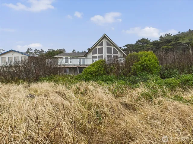 a front view of a house with a yard and mountain view in back