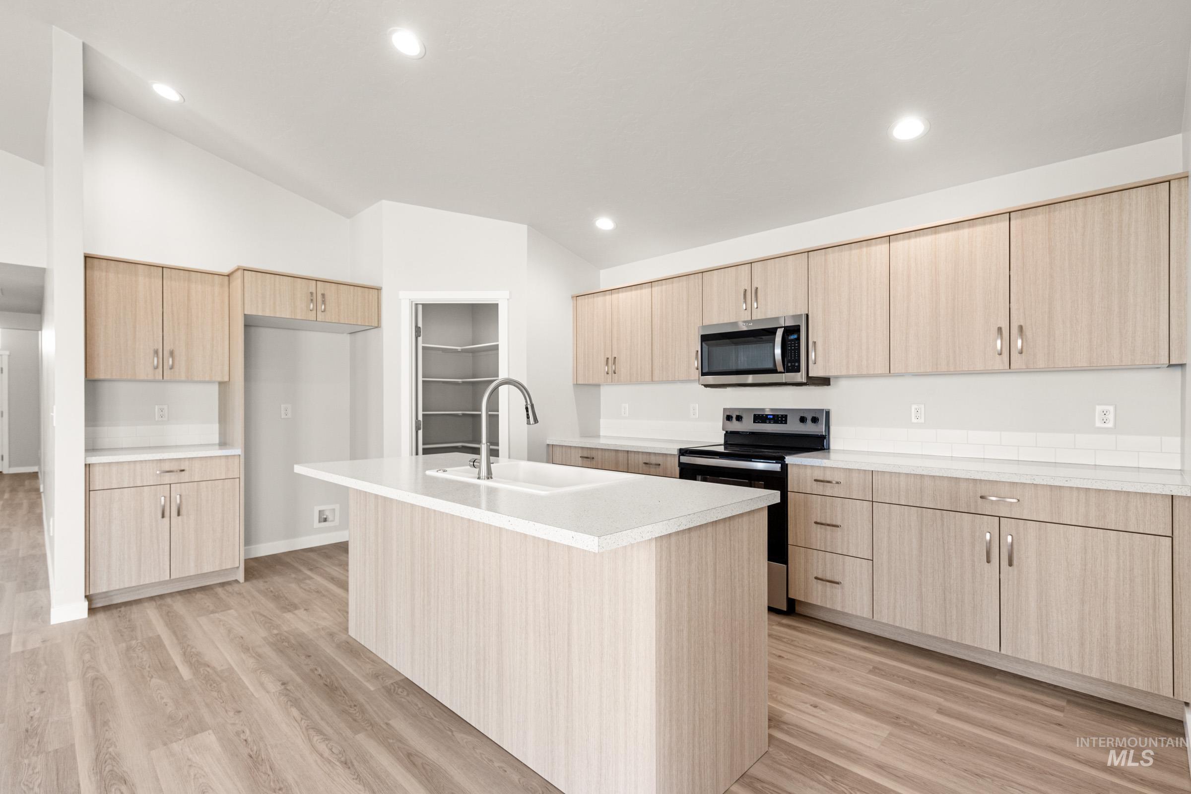 13728 Redway Court Caldwell, ID 83607 - Photo 4 of 19 Kitchen with stainless steel appliances, a kitchen island with sink, light countertops, light wood-style floors, and light wood finish cabinets