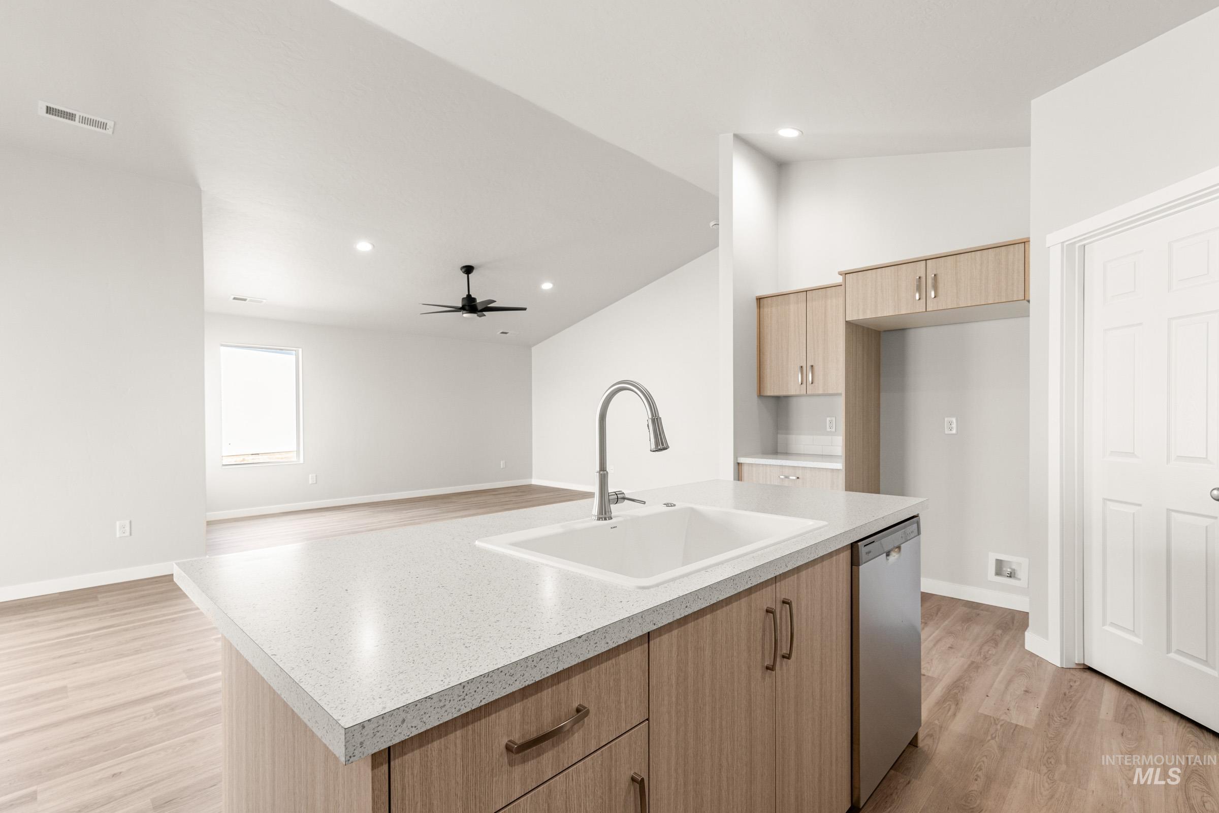 13728 Redway Court Caldwell, ID 83607 - Photo 19 of 19 Kitchen with light wood finished floors, vaulted ceiling, open floor plan, light wood finish cabinets, and a kitchen island with sink