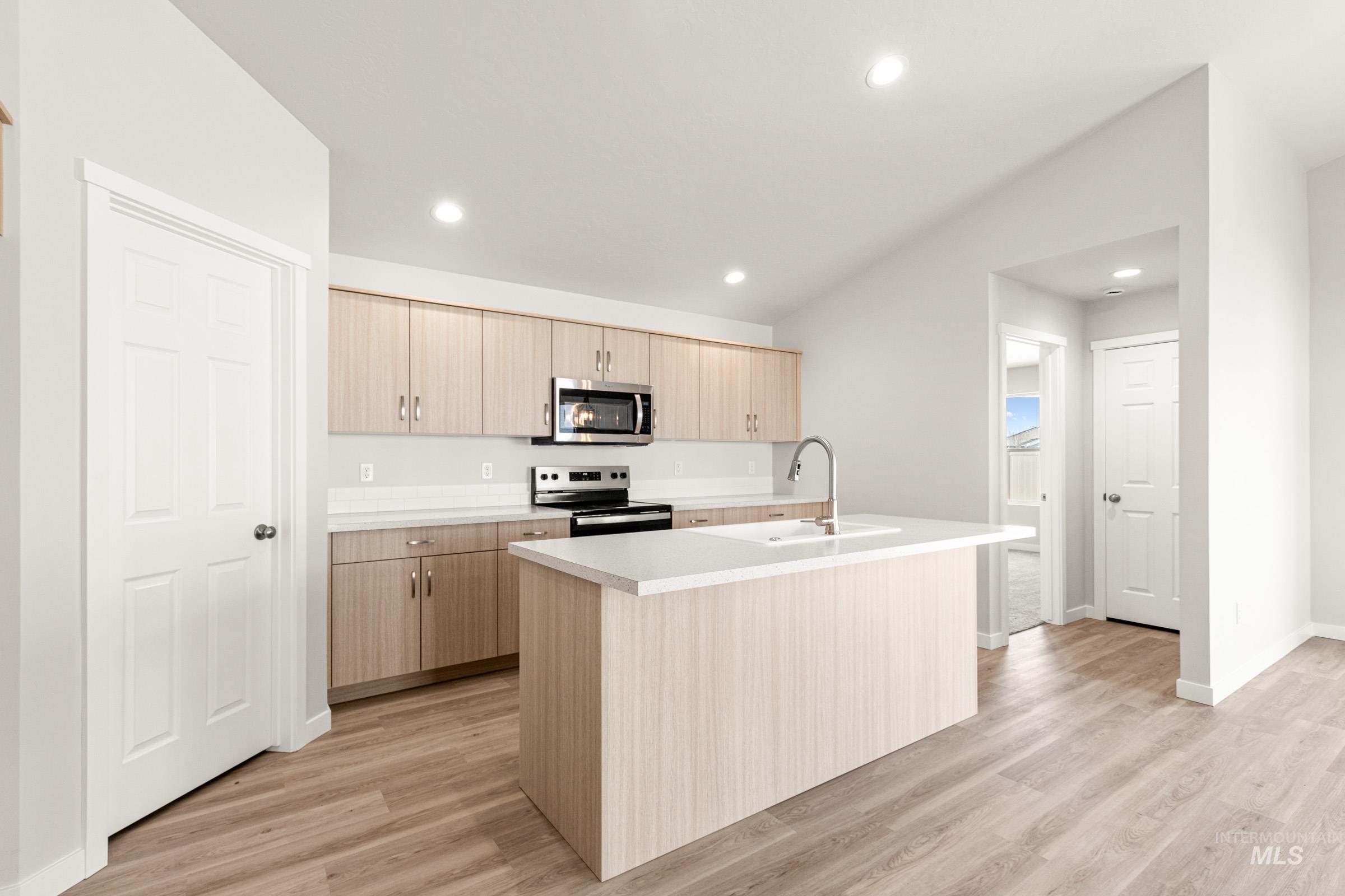 13728 Redway Court Caldwell, ID 83607 - Photo 6 of 19 Kitchen featuring a center island with sink, light countertops, light wood-type flooring, stainless steel appliances, and light wood finish cabinets