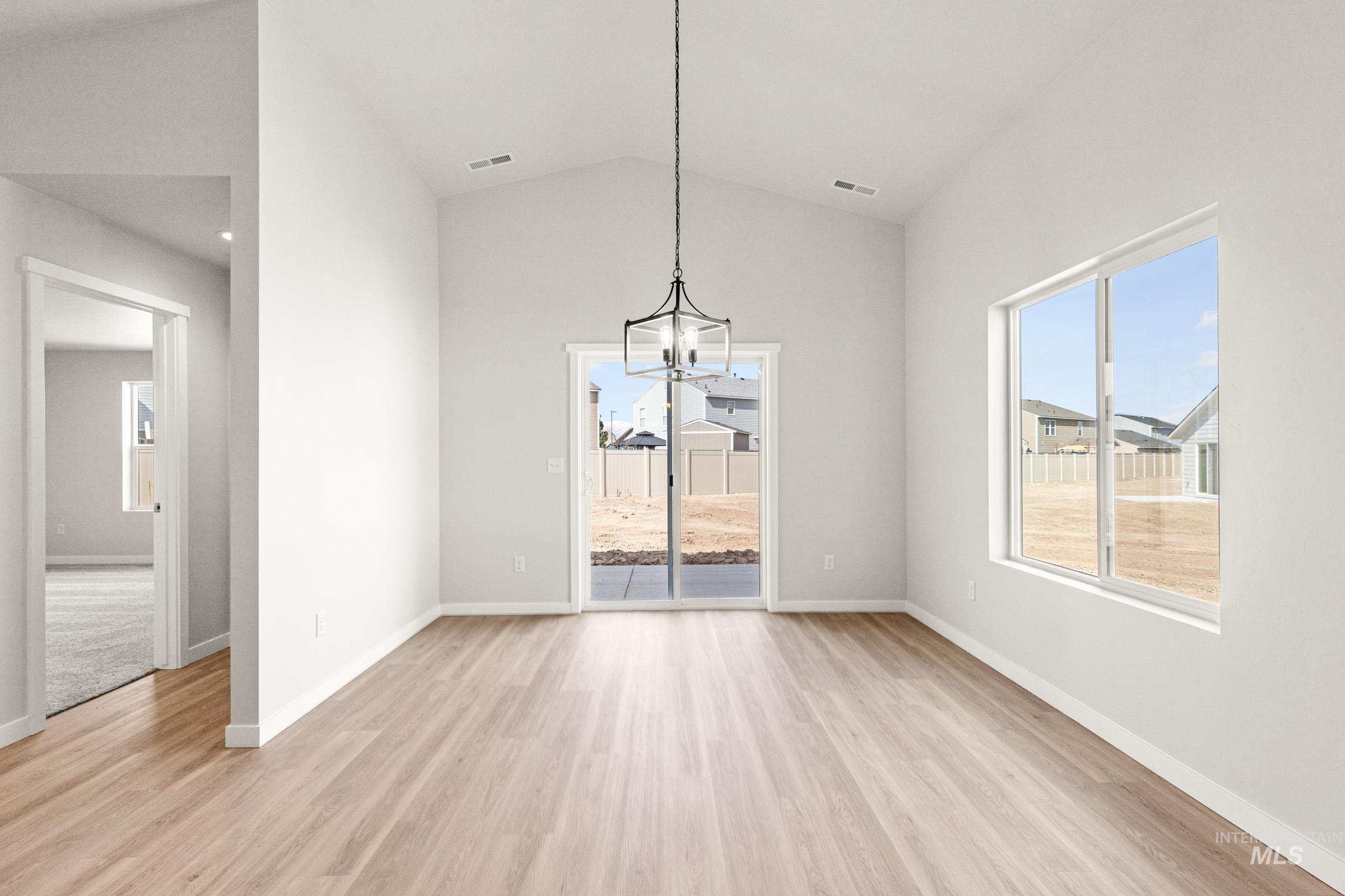 13728 Redway Court Caldwell, ID 83607 - Photo 7 of 19 Unfurnished dining area featuring hanging lights, light wood-type flooring, lofted ceiling, and plenty of natural light