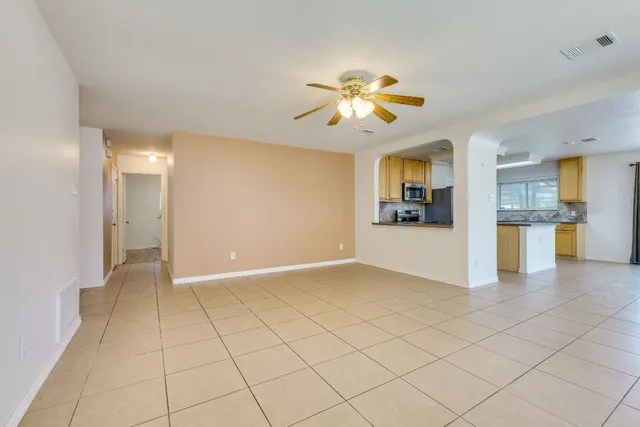 an empty room with a chandelier fan and windows