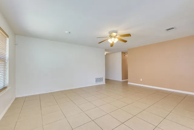 a view of an empty room with window and chandelier fan