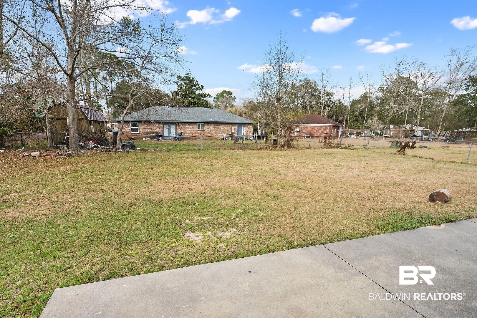 635 East Azalea Avenue Foley, AL 36535 - Photo 16 of 18 Expansive grassy yard area featuring mature trees and a concrete patio