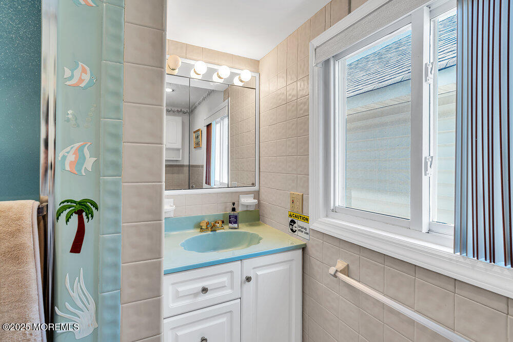115 Beach Front Manasquan, NJ 08736 - Photo 29 of 32 a bathroom with a granite countertop sink a mirror a vanity and a shower