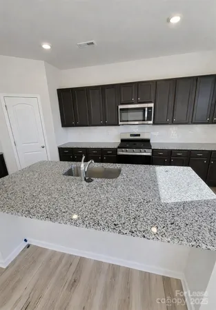 a kitchen with stainless steel appliances granite countertop a sink stove and cabinets