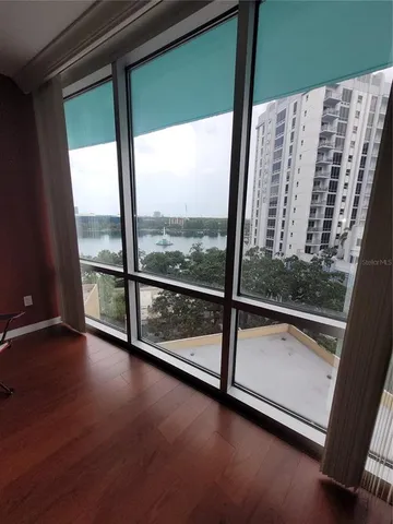 a view of an empty room with wooden floor and windows