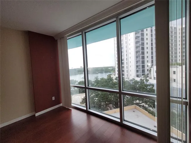 a view of an empty room with wooden floor and windows