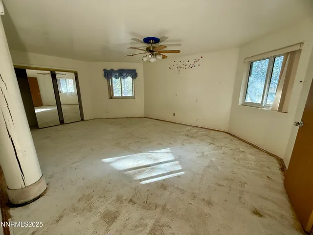 a view of a big room with windows and chandelier fan