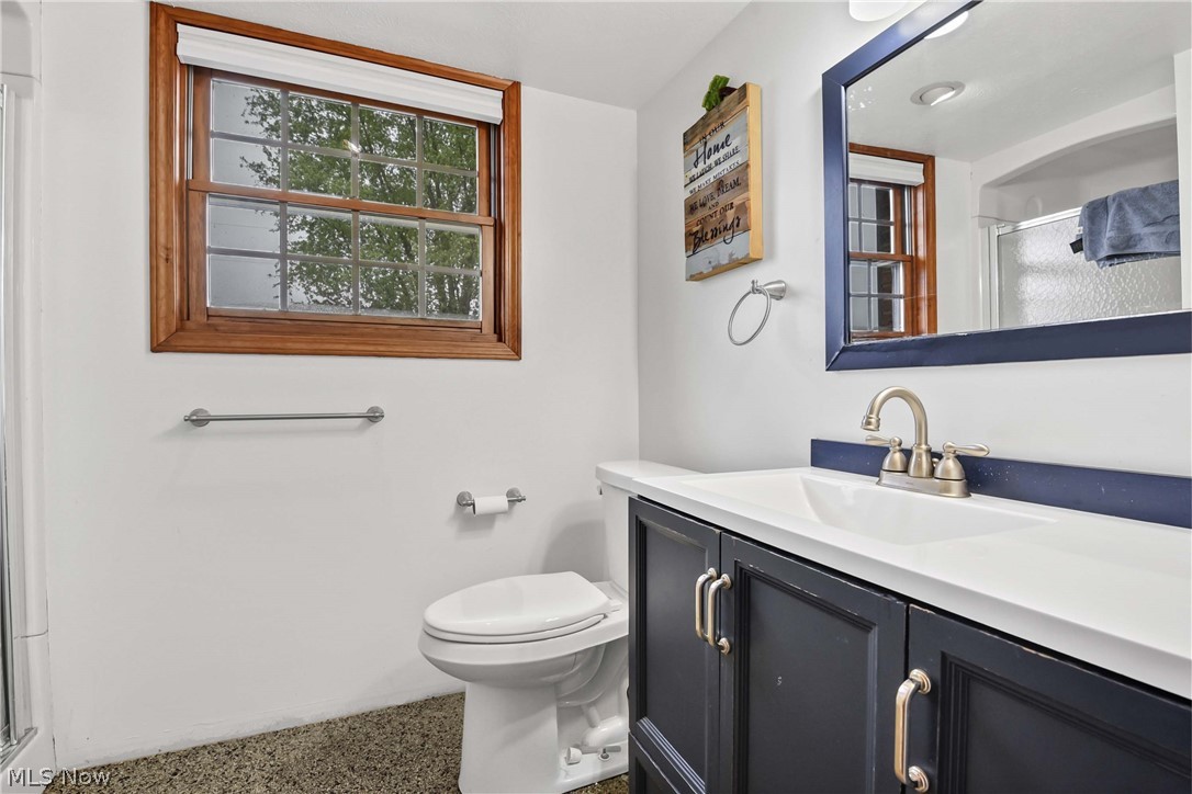 9550 Spencer Road Homerville, OH 44235 - Photo 26 of 50 2nd Floor Bathroom with walk-in-shower and featuring a dark blue vanity with silver-tone hardware, a white countertop with integrated sink, and a framed mirror