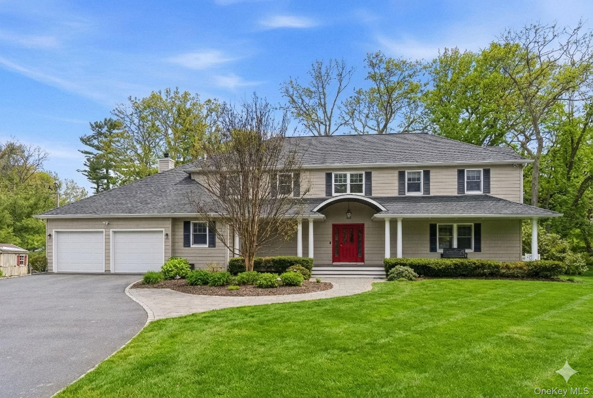 a front view of a house with a garden and trees