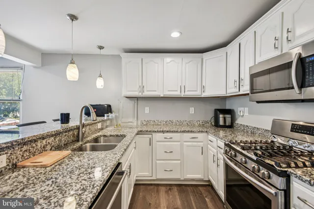 a kitchen with granite countertop a sink a stove and cabinets