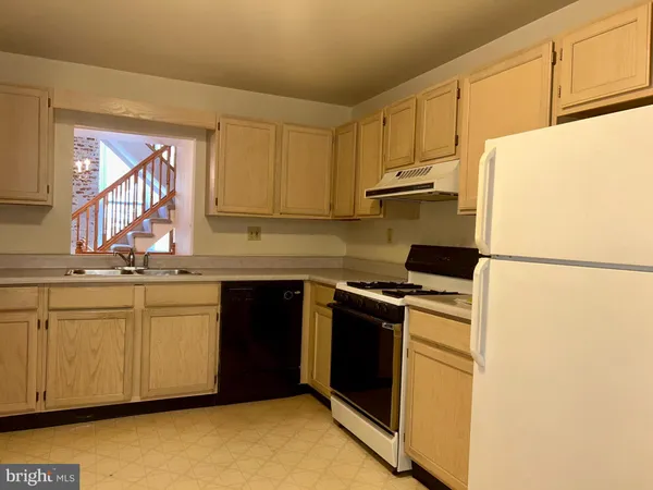 a kitchen with stainless steel appliances granite countertop a refrigerator a stove a sink and white cabinets