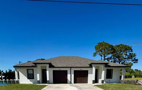 a view of a white house with a big yard and large tree