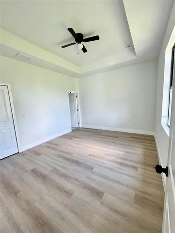 an empty room with wooden floor fan and windows