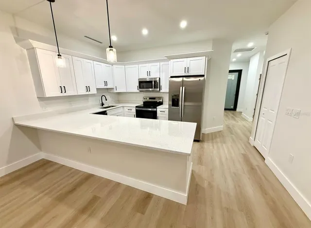 a kitchen with stainless steel appliances a refrigerator sink and wooden floor