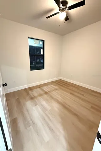 an empty room with a ceiling fan and window