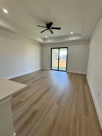 an empty room with wooden floor ceiling fan and windows