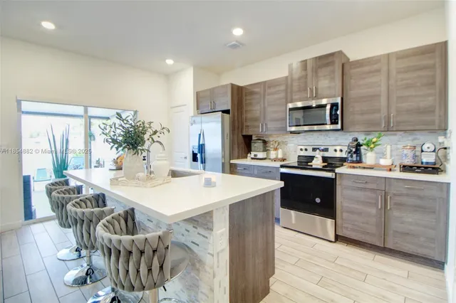 a kitchen with stainless steel appliances kitchen island granite countertop a stove a sink a microwave and a refrigerator