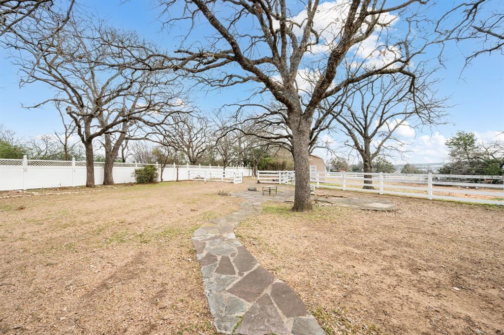 7260 Hudson Cemetery Road Mansfield, TX 76063 - Photo 32 of 40 Expansive outdoor space featuring mature trees, a flagstone pathway, and white fencing enclosing the perimeter