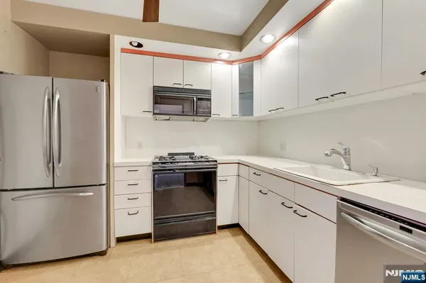 a kitchen with stainless steel appliances white cabinets and a refrigerator
