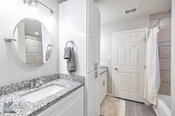 a en suite bathroom with a granite countertop sink and a mirror