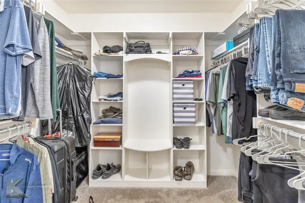 a view of walk in closet with clothes and shoes