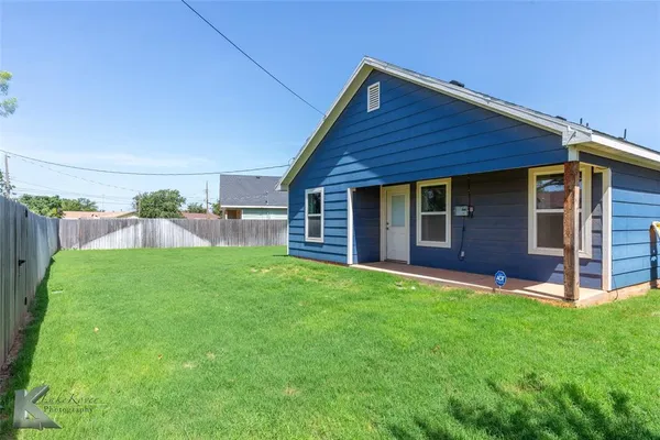 a view of a backyard with table and chairs and wooden fence
