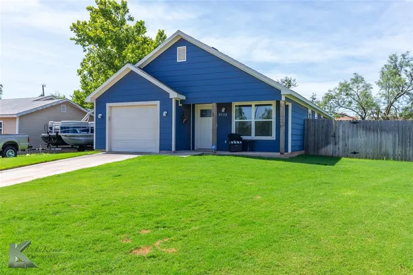 a view of a house with a yard plants and large tree