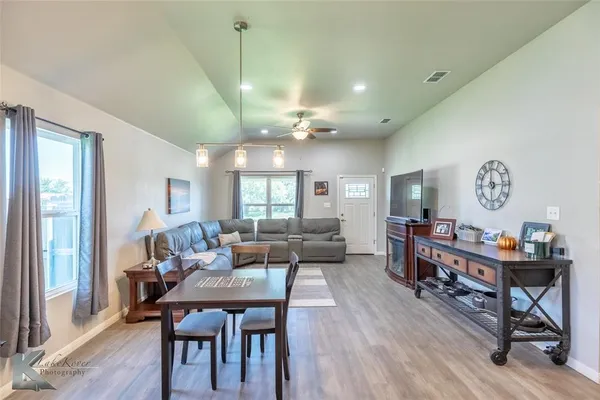 a view of a dining room and livingroom with furniture wooden floor a rug a painting and a chandelier