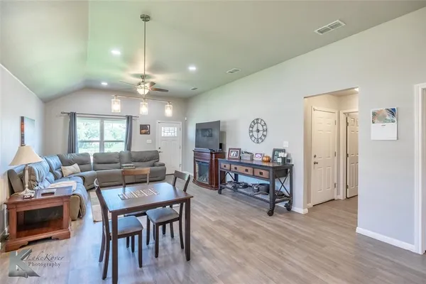 a living room with furniture kitchen view and a wooden floor