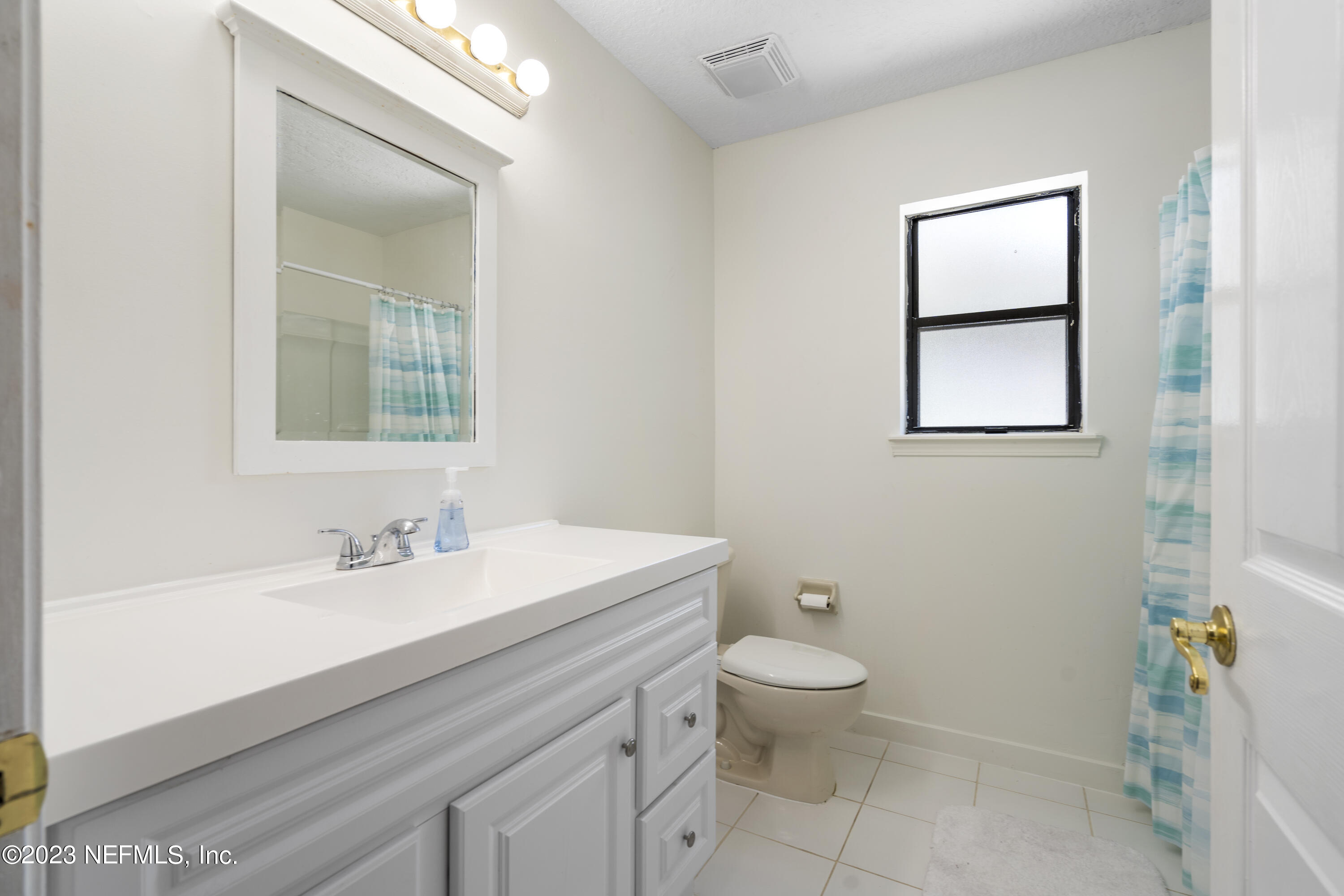 870 Fleming Street Fleming Island, FL 32003 - Photo 23 of 48 a bathroom with a sink a toilet a window and mirror