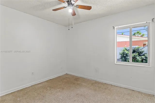 an empty room with a window and a fan