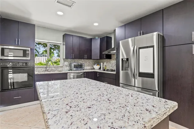 a kitchen with granite countertop a refrigerator and a stove top oven