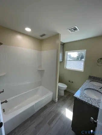 a bathroom with a granite countertop sink a toilet and bathtub