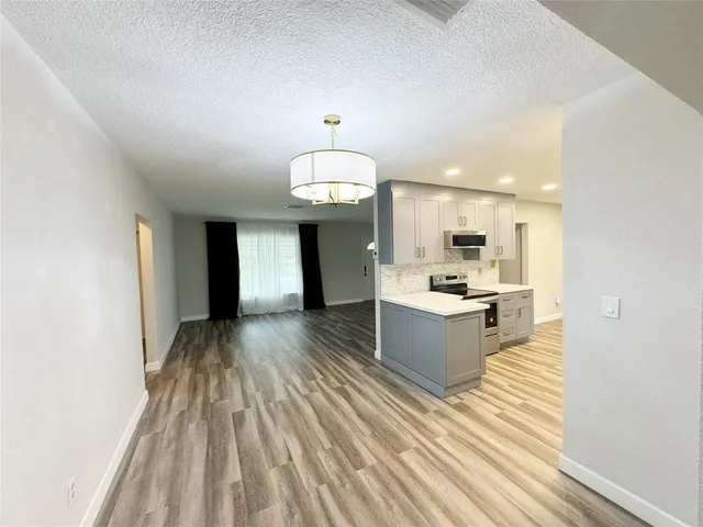 a large white kitchen with stainless steel appliances lots of counter space and wooden floor