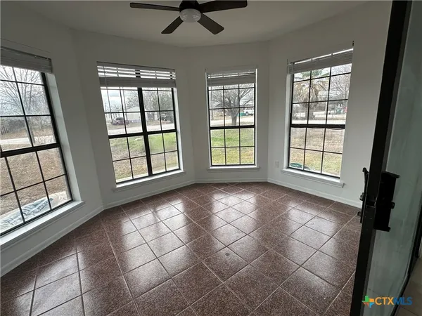 an empty room with windows and ceiling fan