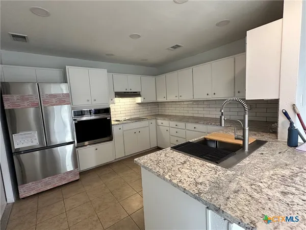 a kitchen with granite countertop a sink a stove and refrigerator