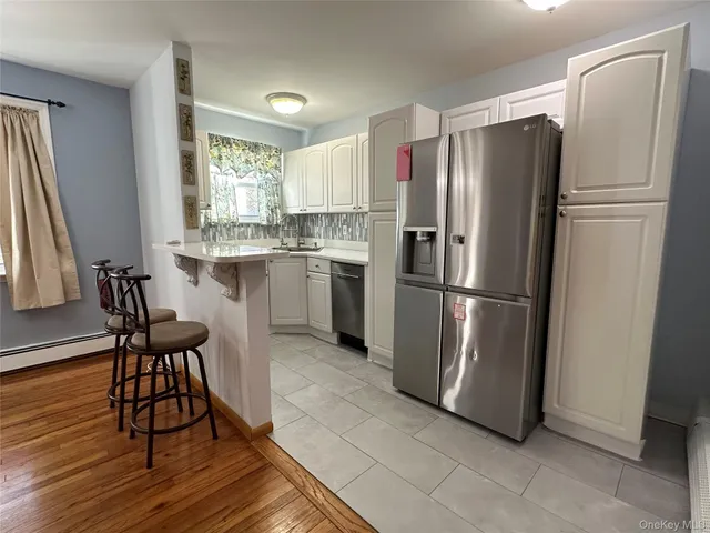 a kitchen with stainless steel appliances granite countertop a refrigerator a stove a sink and dishwasher with wooden floor
