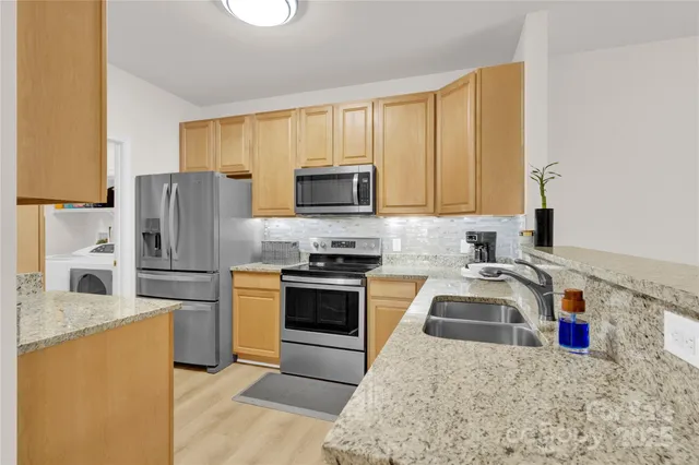 a kitchen with granite countertop a sink stainless steel appliances and cabinets