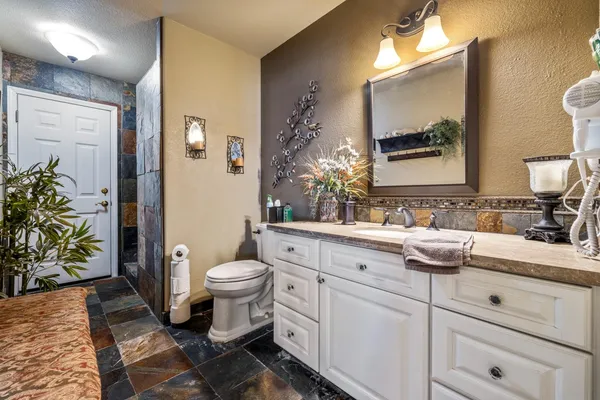 a bathroom with a granite countertop sink mirror vanity and toilet