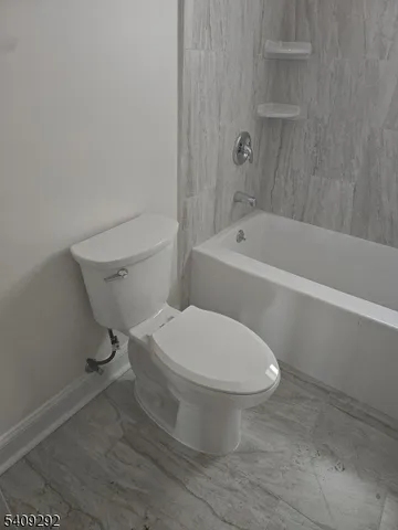 a white toilet sitting next to a bath tub