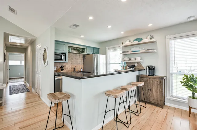 a kitchen with stainless steel appliances a dining table chairs and wooden floor