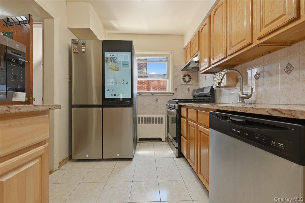 79 Wellington Road Elmont, NY 11003 - Photo 10 of 33 Efficient kitchen featuring a stainless steel refrigerator with an integrated display, wood-finish cabinetry, a gas range, and a stainless steel dishwasher