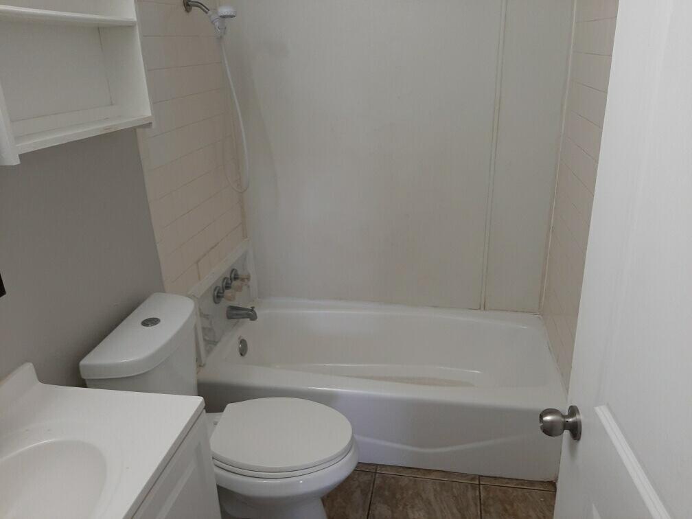 2403 East 5th Street Lubbock, TX 79403 - Photo 2 of 8 a white toilet and tub sitting next to a bathroom sink