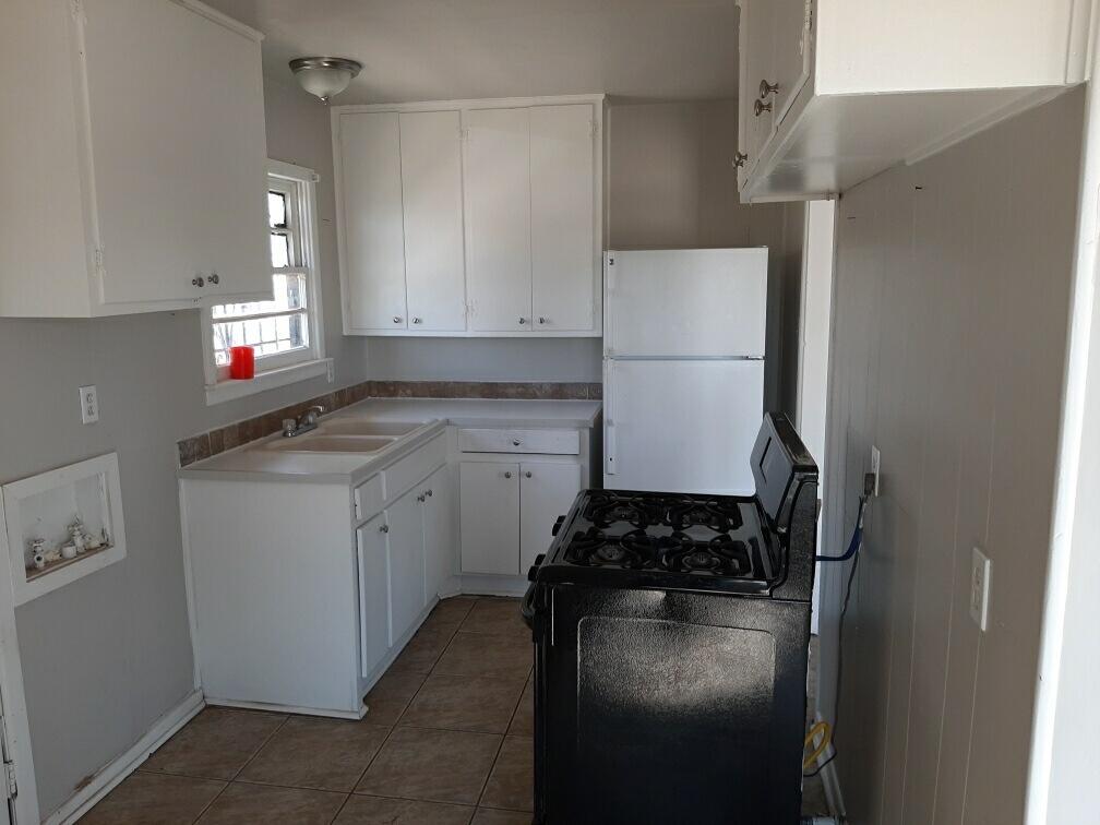 2403 East 5th Street Lubbock, TX 79403 - Photo 6 of 8 a kitchen with a refrigerator a stove a microwave and cabinets