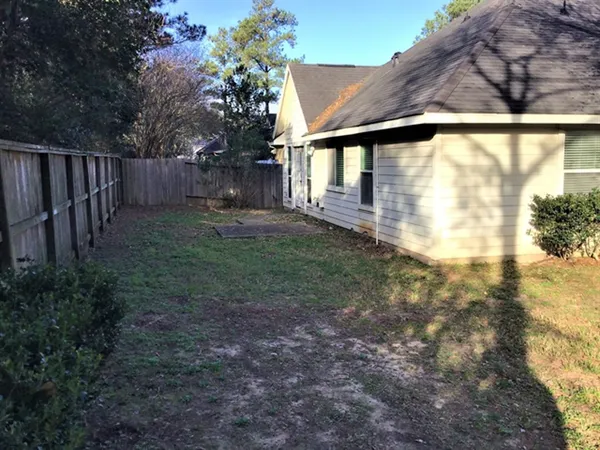a view of a backyard with wooden fence and a large tree