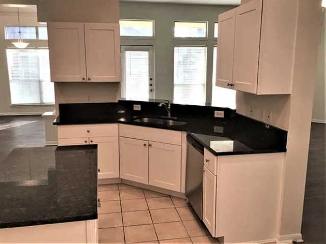 a kitchen with granite countertop white cabinets and black appliances